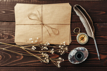 Top view of an old paper on brown wooden texture background with feather
