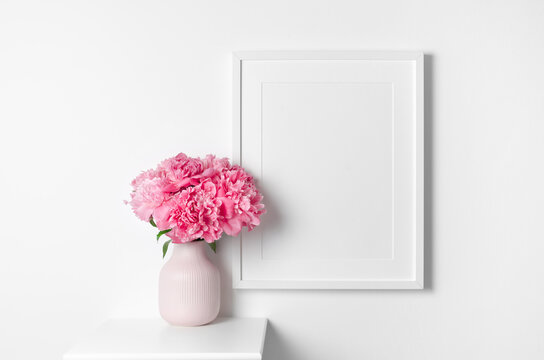 White picture frame mockup on wall with pink peony flowers bouquet