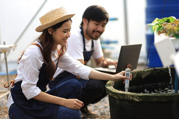 Modern farmer working in a hydroponics greenhouse uses laptop to control various systems in the...