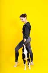 Fototapeta na wymiar Excited girl dancing with border collie. Studio portrait lady looking at dog with surprised smile.