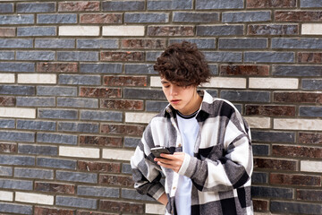 Fototapeta na wymiar young man reading message on phone against a brick wall