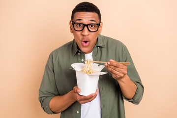 Photo of funky impressed guy dressed khaki shirt spectacles eating noodles isolated beige color background