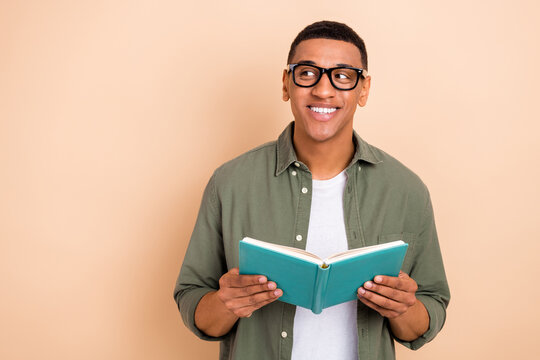 Photo of funky dreamy guy dressed khaki shirt spectacles enjoying novel looking empty space isolated beige color background