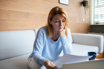 Obraz premium Mid adult woman going over bills at home