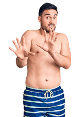 Fototapeta premium Young handsome man wearing swimwear afraid and terrified with fear expression stop gesture with hands, shouting in shock. panic concept.