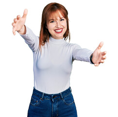 Fototapeta na wymiar Redhead young woman wearing casual turtleneck sweater looking at the camera smiling with open arms for hug. cheerful expression embracing happiness.