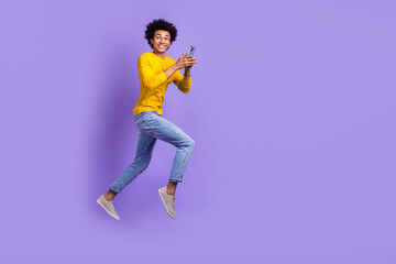 Fototapeta na wymiar Full body size photo of funky positive young guy running fast speed use gadget texting online sms isolated over violet color background