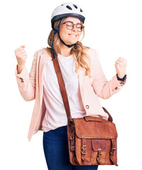 Young caucasian woman wearing bike helmet and leather bag very happy and excited doing winner gesture with arms raised, smiling and screaming for success. celebration concept.
