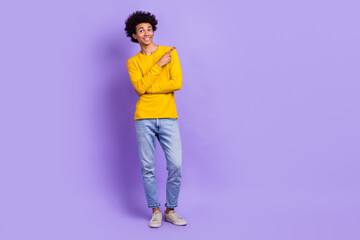 Full length photo of funky satisfied guy wear stylish yellow pullover indicating at offer empty space isolated on violet color background