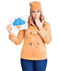 Young caucasian woman holding thunder draw covering mouth with hand, shocked and afraid for mistake. surprised expression