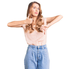 Young beautiful caucasian woman with blond hair wearing casual clothes doing thumbs up and down, disagreement and agreement expression. crazy conflict