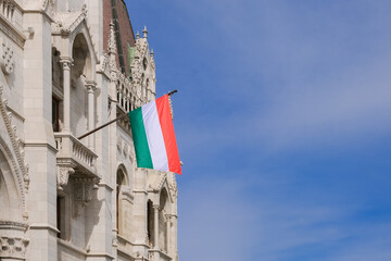 National Hungarian flag on wall of Parliament building and blue sky background