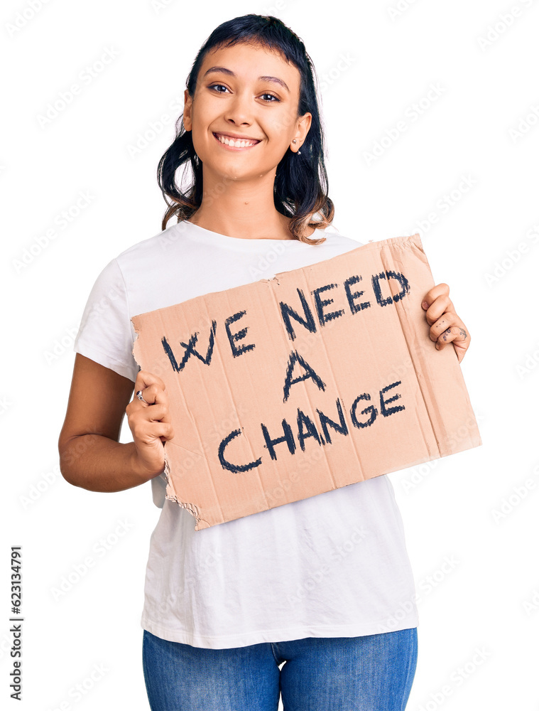 Sticker young woman holding we need a change banner looking positive and happy standing and smiling with a c