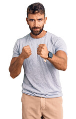 Young hispanic man wearing casual clothes ready to fight with fist defense gesture, angry and upset...