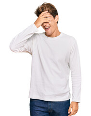 Handsome caucasian man wearing casual white sweater smiling and laughing with hand on face covering eyes for surprise. blind concept.