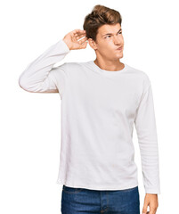 Handsome caucasian man wearing casual white sweater confuse and wondering about question. uncertain with doubt, thinking with hand on head. pensive concept.