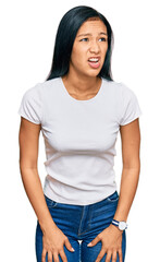 Obraz premium Beautiful hispanic woman wearing casual white tshirt angry and mad screaming frustrated and furious, shouting with anger. rage and aggressive concept.