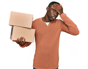 Young african american man holding delivery package stressed and frustrated with hand on head, surprised and angry face