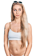 Fototapeta premium Beautiful young blonde woman wearing bikini smiling looking to the side and staring away thinking.