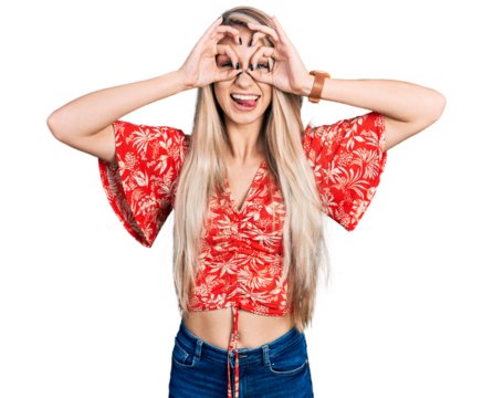 Beautiful young blonde woman wearing summer shirt doing ok gesture like binoculars sticking tongue out, eyes looking through fingers. crazy expression.