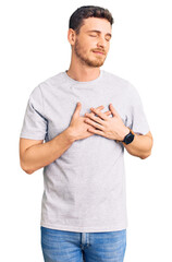 Handsome young man with bear wearing casual tshirt smiling with hands on chest with closed eyes and grateful gesture on face. health concept.