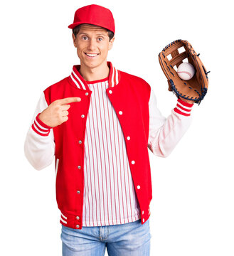 Young handsome man wearing baseball uniform holding golve and ball smiling happy pointing with hand and finger