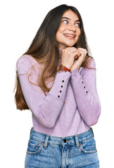 Young beautiful teen girl wearing turtleneck sweater laughing nervous and excited with hands on chin looking to the side