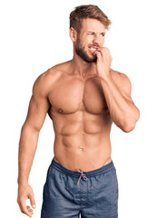 Fototapeta premium Young caucasian man standing shirtless looking stressed and nervous with hands on mouth biting nails. anxiety problem.