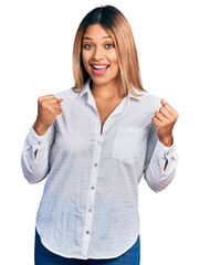 Young hispanic woman wearing casual white shirt celebrating surprised and amazed for success with...