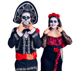 Young couple wearing mexican day of the dead costume over background smiling with open mouth, fingers pointing and forcing cheerful smile