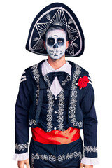 Young man wearing day of the dead costume over background relaxed with serious expression on face. simple and natural looking at the camera.