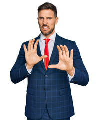 Handsome man with beard wearing business suit and tie disgusted expression, displeased and fearful...