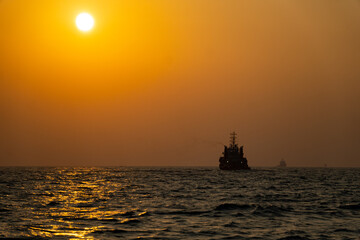Obraz premium sunset creating ship silhouette offshore