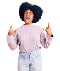 Young african american girl wearing casual clothes shouting with crazy expression doing rock symbol with hands up. music star. heavy concept.