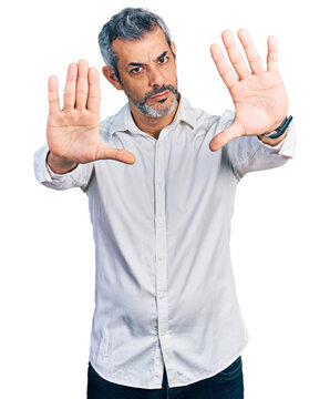 Middle age hispanic with grey hair wearing casual white shirt doing frame using hands palms and fingers, camera perspective