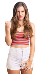 Fototapeta premium Beautiful caucasian young woman wearing casual clothes angry and mad raising fist frustrated and furious while shouting with anger. rage and aggressive concept.