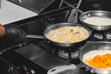 Risotto food cooking in a pan on a stove with a hand shaking the pan