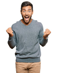 Handsome hispanic man wearing casual clothes celebrating surprised and amazed for success with arms...