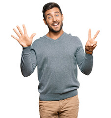 Fototapeta premium Handsome hispanic man wearing casual clothes showing and pointing up with fingers number seven while smiling confident and happy.