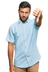 Handsome hispanic man wearing casual clothes looking unhappy and angry showing rejection and negative with thumbs down gesture. bad expression.