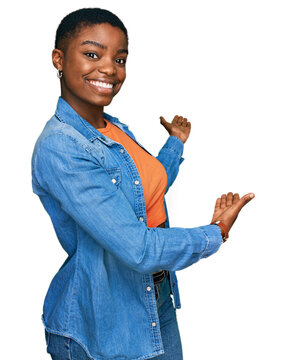 Young african american woman wearing casual clothes inviting to enter smiling natural with open hand