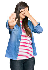 Young brunette woman wearing casual clothes covering eyes with hands and doing stop gesture with sad and fear expression. embarrassed and negative concept.