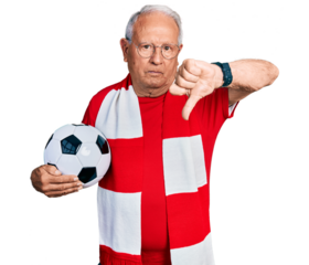 Senior man with grey hair football hooligan holding ball looking unhappy and angry showing rejection and negative with thumbs down gesture. bad expression.