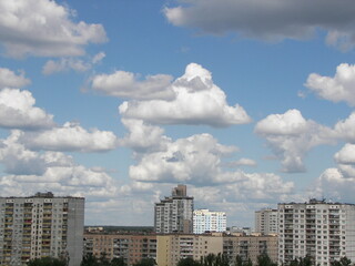 Fototapeta na wymiar white cumulus clouds in the blue sky over high-rise city buildings