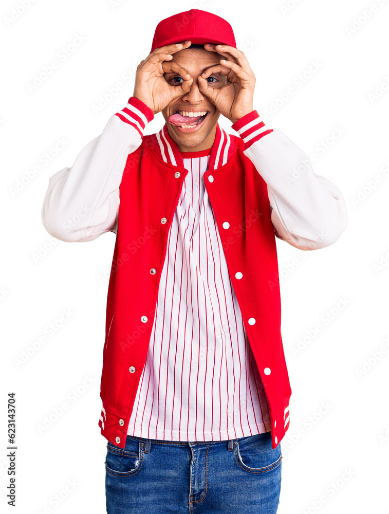 Wall mural Young african amercian man wearing baseball uniform doing ok gesture like binoculars sticking tongue out, eyes looking through fingers. crazy expression.