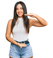 Young beautiful hispanic girl wearing casual clothes gesturing with hands showing big and large size sign, measure symbol. smiling looking at the camera. measuring concept.