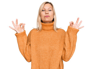 Middle age caucasian woman wearing casual winter sweater relaxed and smiling with eyes closed doing meditation gesture with fingers. yoga concept.