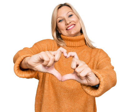 Middle age caucasian woman wearing casual winter sweater smiling in love doing heart symbol shape with hands. romantic concept.
