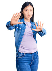 Young beautiful chinese woman pregnant expecting baby doing stop gesture with hands palms, angry and frustration expression