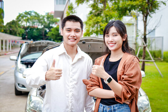Asian man and woman driving a car accident on the road Both of them smiled, thumbs up, satisfied, clearing the insurance together. Transportation concept. car insurance
